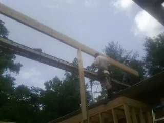Carpenter setting a ridge beam over a new addition frame — Ice Dam Removal by Roofing Brothers in Foster