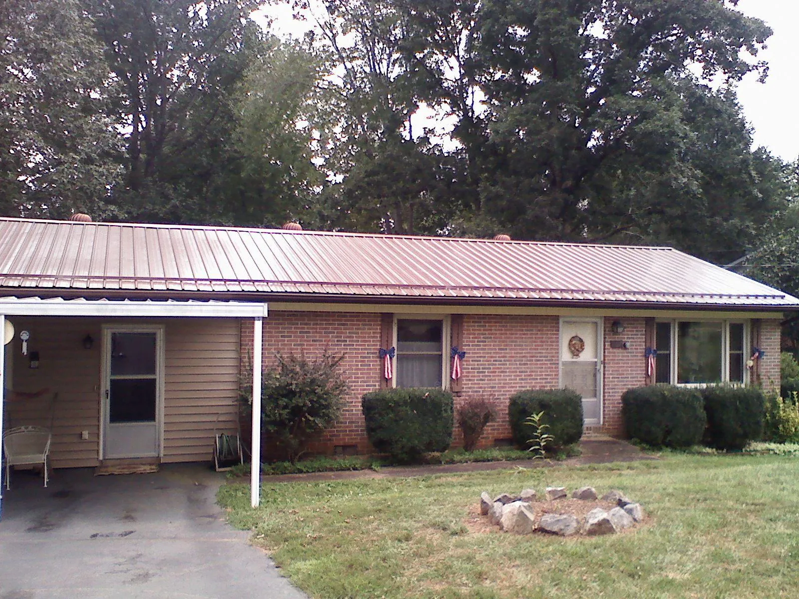 Bronze metal roof and carport on a brick ranch home — Roof Repair work by our crew in Foster