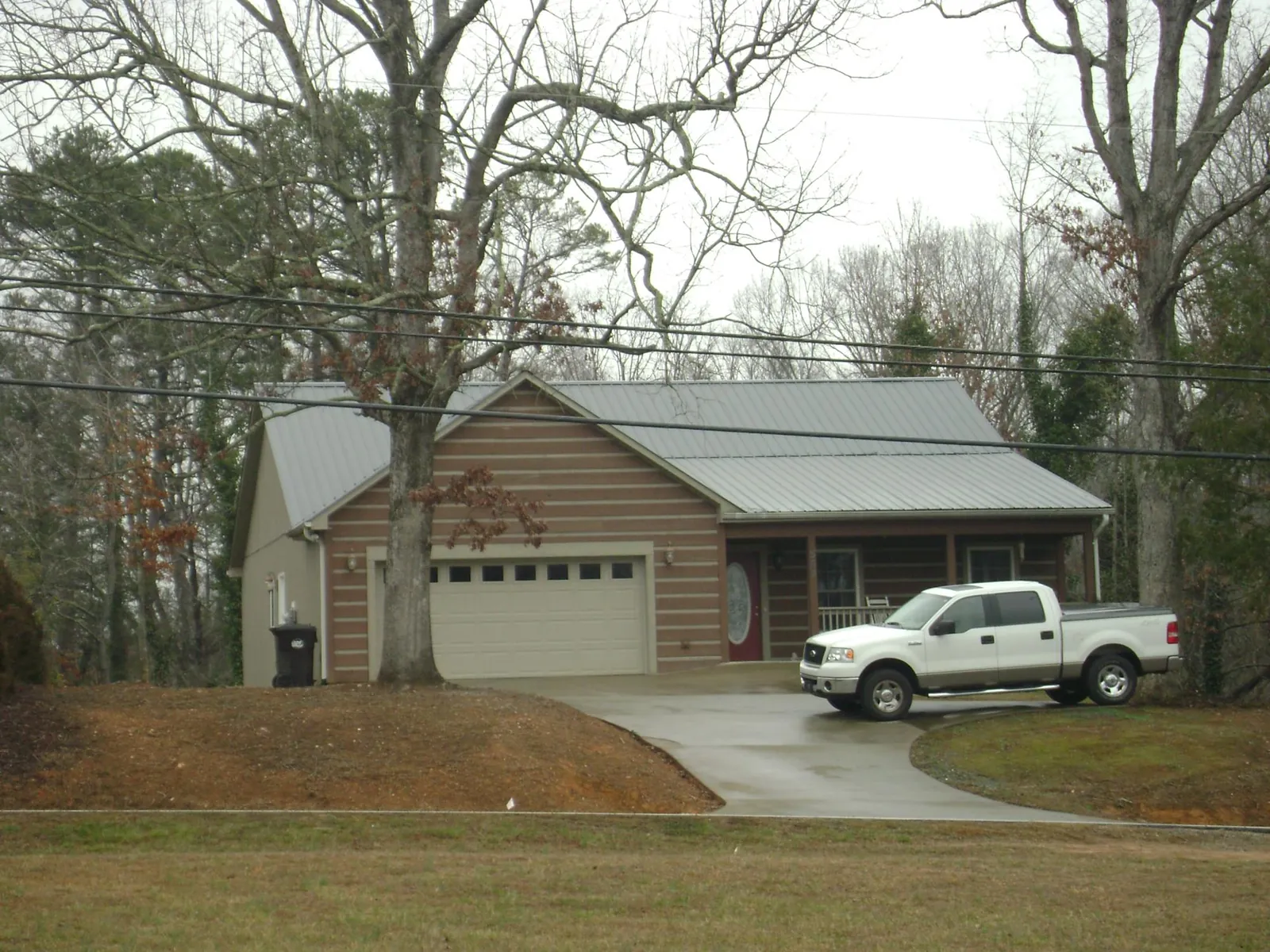 Gray metal roof on a log sided house with an attached two car garage in Foster
